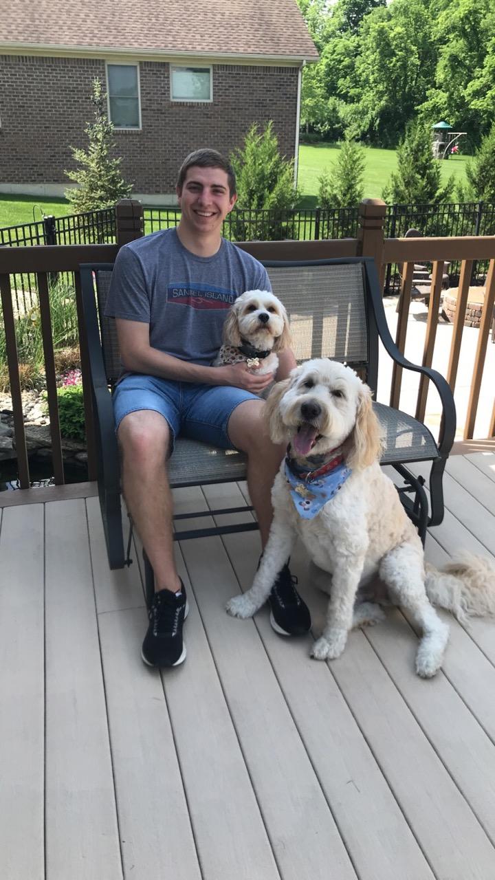 Connor sitting on a bench outside with his two dogs.